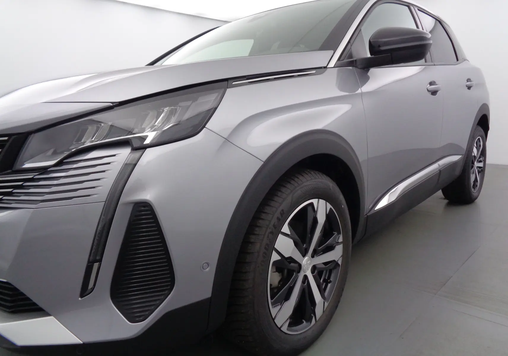 Vue 3/4 avant droit d'un Peugeot 3008 gris Artense métal avec jantes alliage bicolores et phares LED distinctifs.