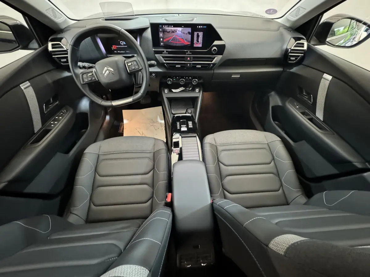 Intérieur noir de la Citroën C4 PureTech 130, vue avant centrée sur le tableau de bord et les sièges cuir.