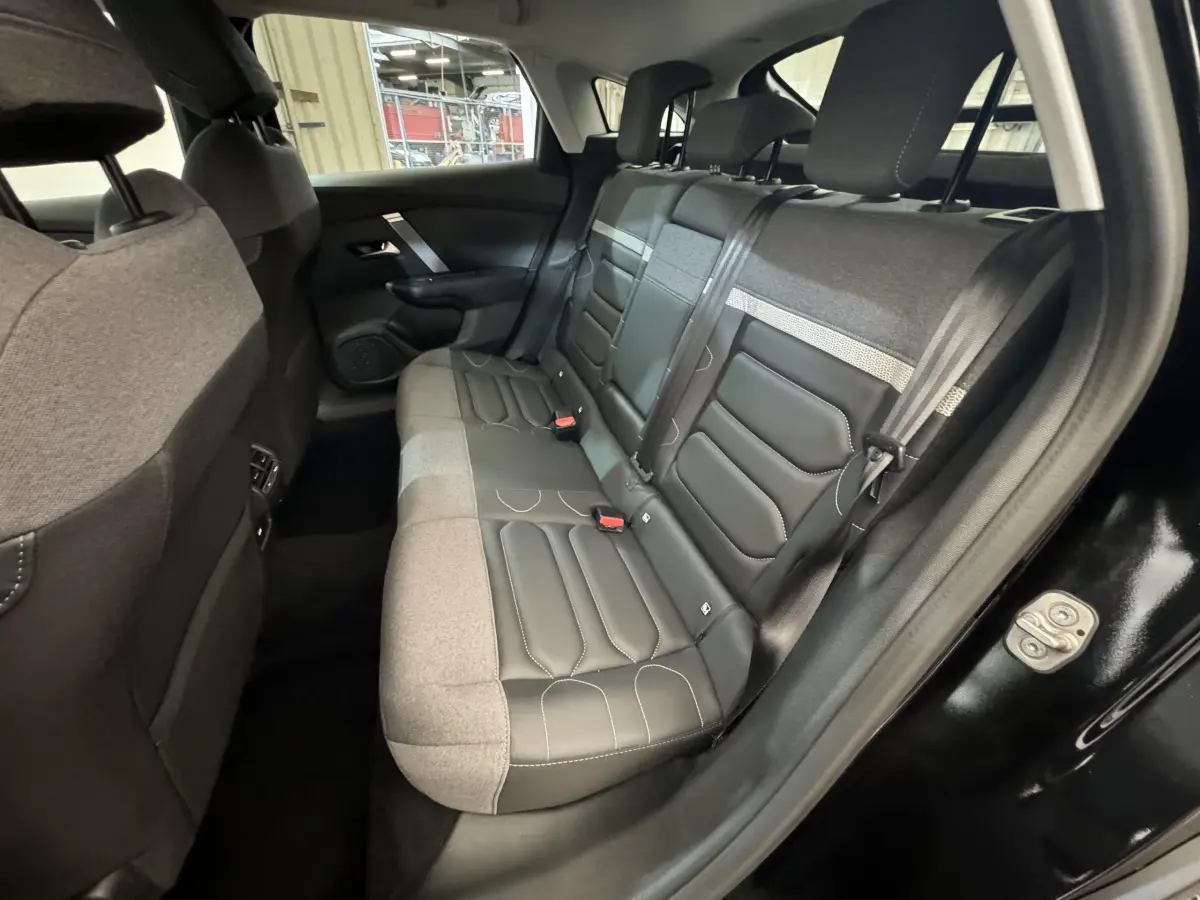 Vue côté gauche de l'habitacle arrière noir d'une Citroën C4 2023 avec sièges bi-matière cuir et tissu gris.