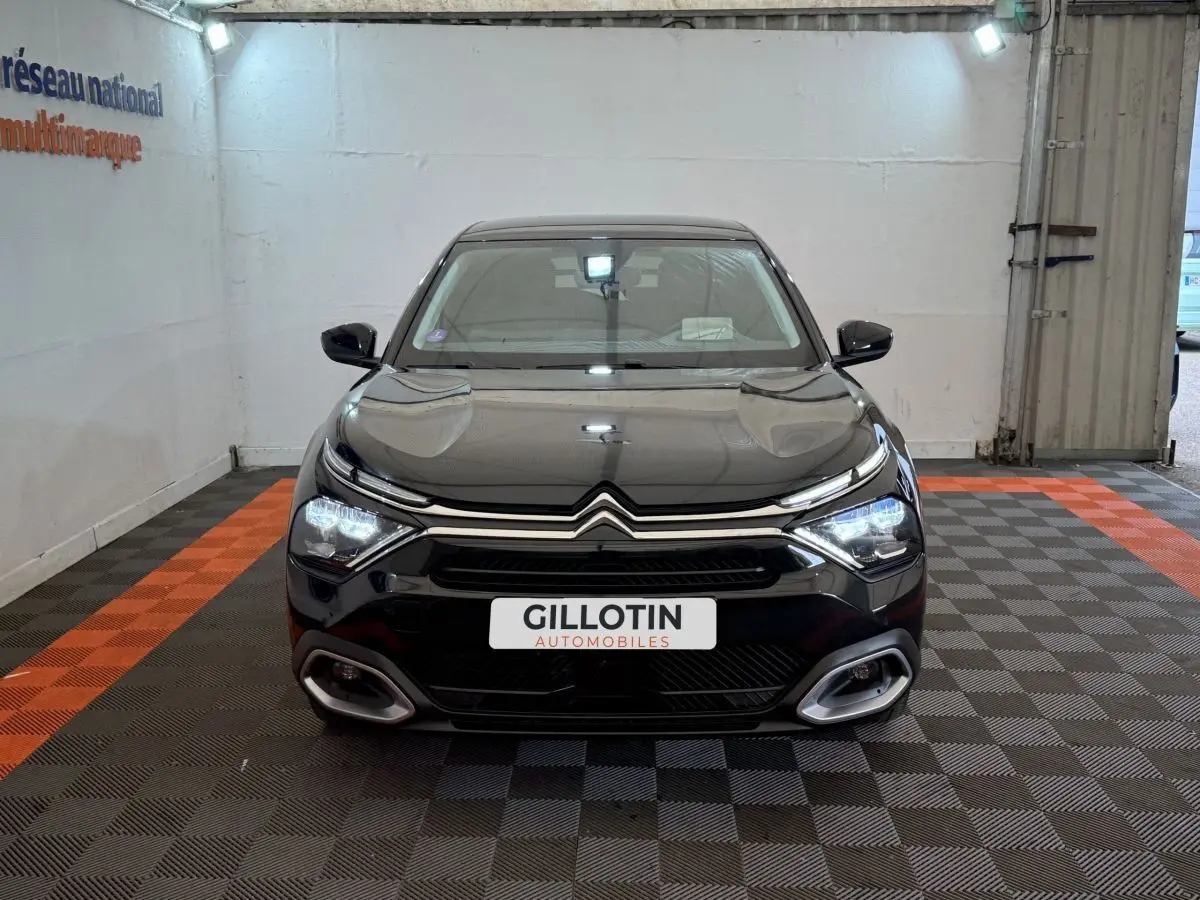 Citroën C4 PureTech 130 noir vue de face en intérieur, phares LED allumés et calandre distinctive.