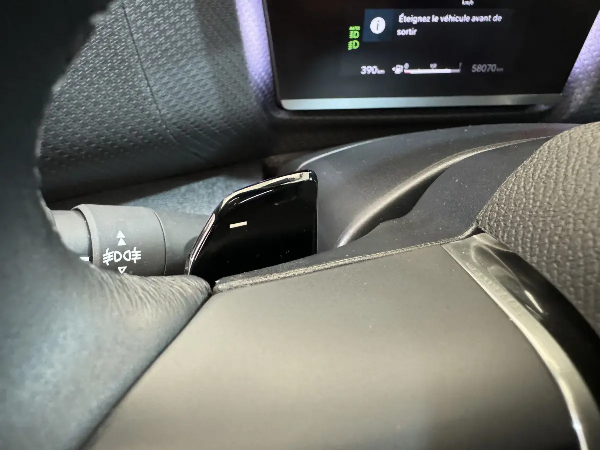 Gros plan sur la palette de changement de vitesses noire et le tableau de bord numérique d'une Citroën C4 PureTech 130 noire.