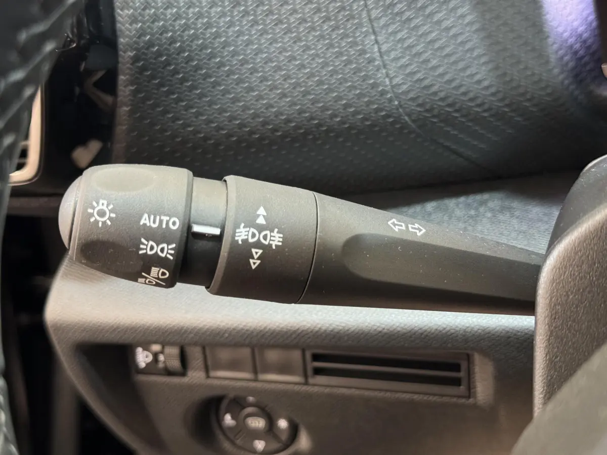 Gros plan sur la commande des phares et clignotants dans l'habitacle noir de la Citroën C4 PureTech 130 EAT8 Shine 2023.