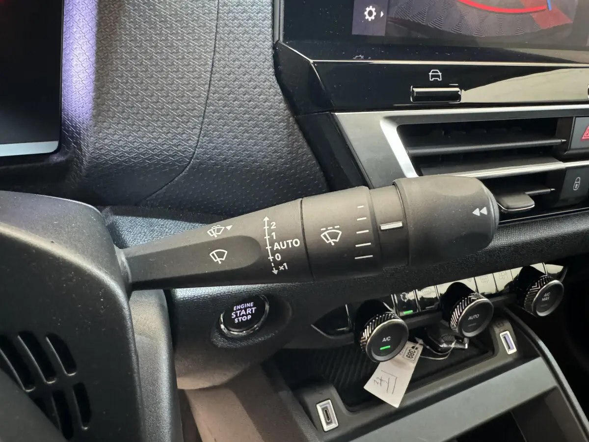 Gros plan sur la commande d’essuie-glace et le bouton start/stop du tableau de bord noir de la Citroën C4 2023 Shine.