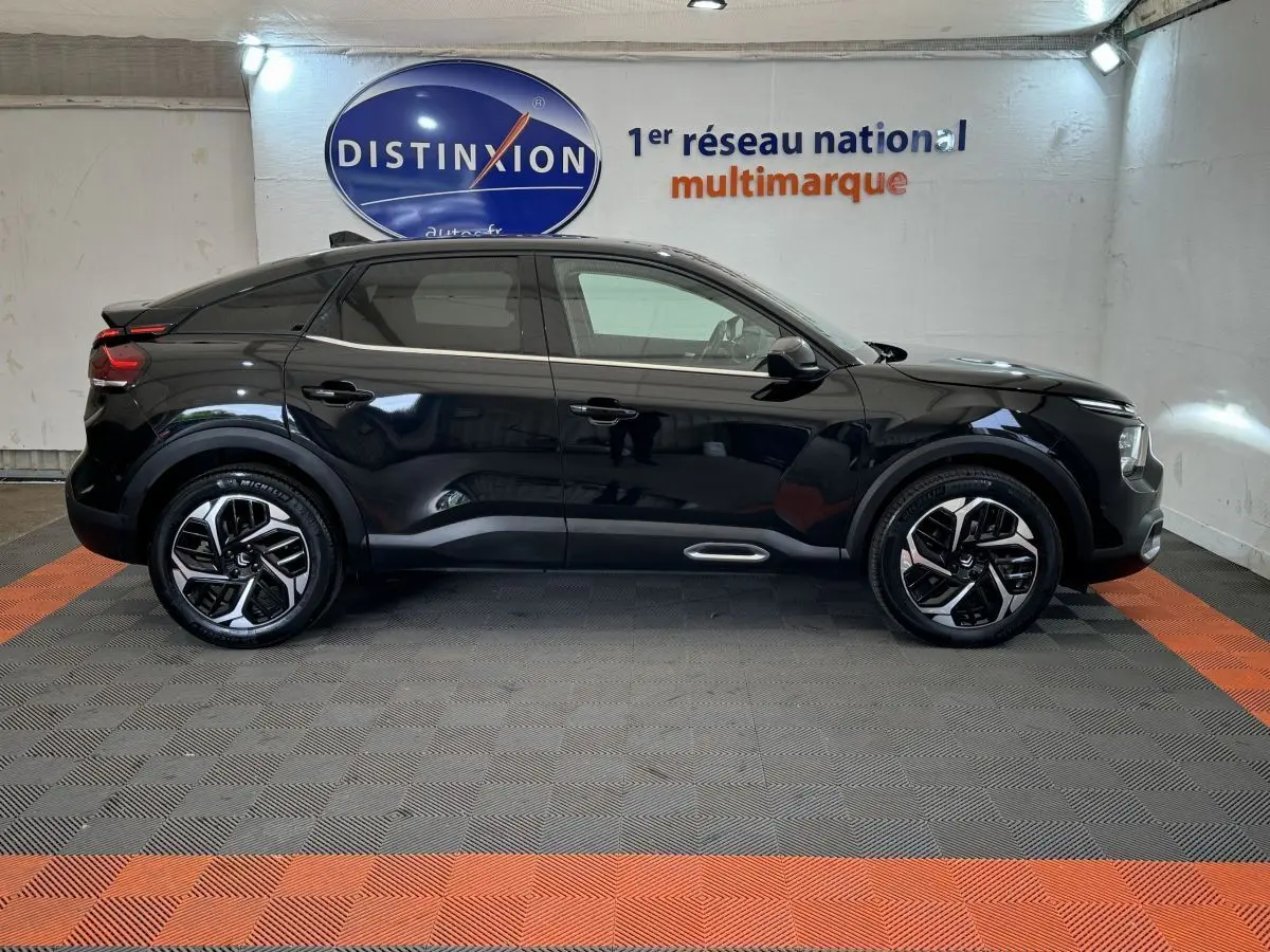 Profil côté gauche d'une Citroën C4 PureTech 130 EAT8 Shine noire, avec jantes alliage et toit noir en showroom.