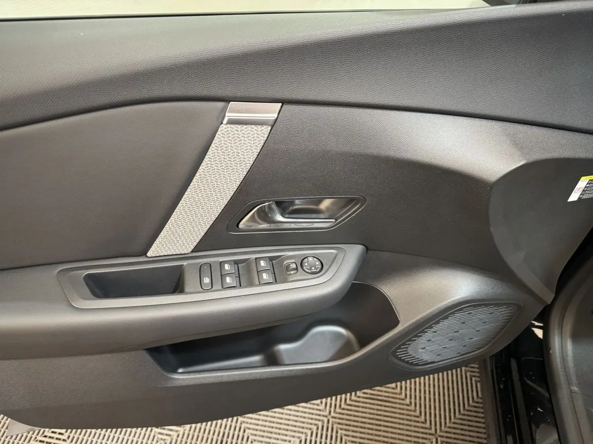 Vue du panneau de porte côté gauche noir de la Citroën C4 PureTech 130 EAT8 Shine avec commandes électriques et insert décoratif clair.