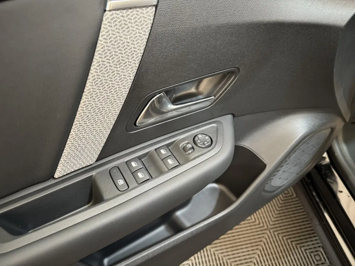 Vue rapprochée de la porte avant gauche noire du Citroën C4 2023 avec commandes électriques et insert décoratif gris.