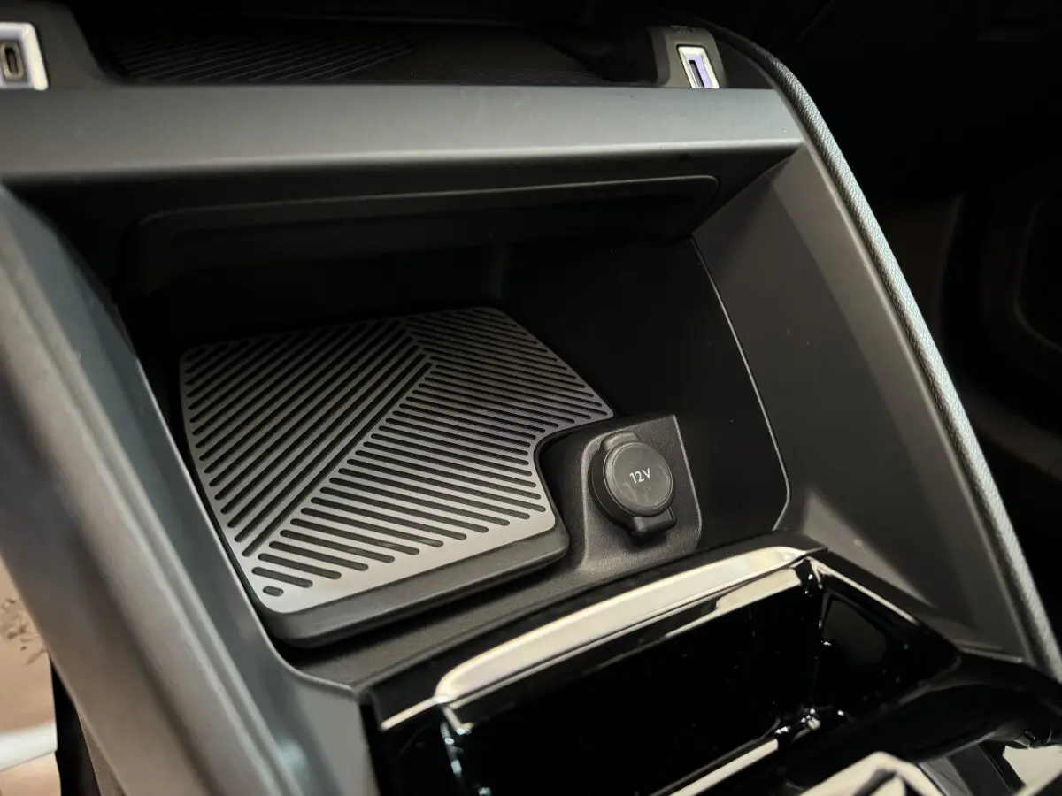 Détail de la console centrale noire d'une Citroën C4 PureTech 130 EAT8 Shine avec prise 12V et surface antidérapante.