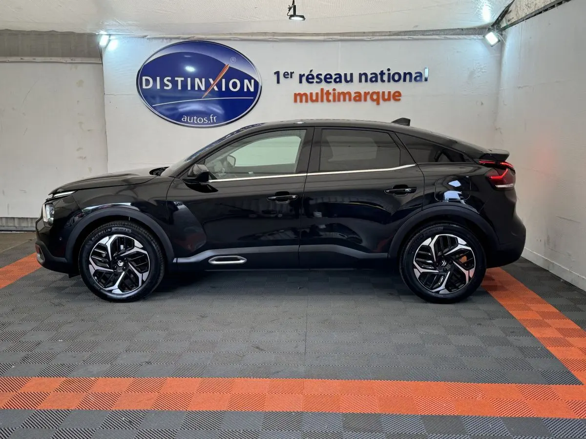 Profil côté gauche d'une Citroën C4 PureTech 130 EAT8 Shine noire, avec jantes modernes et ligne de toit dynamique.