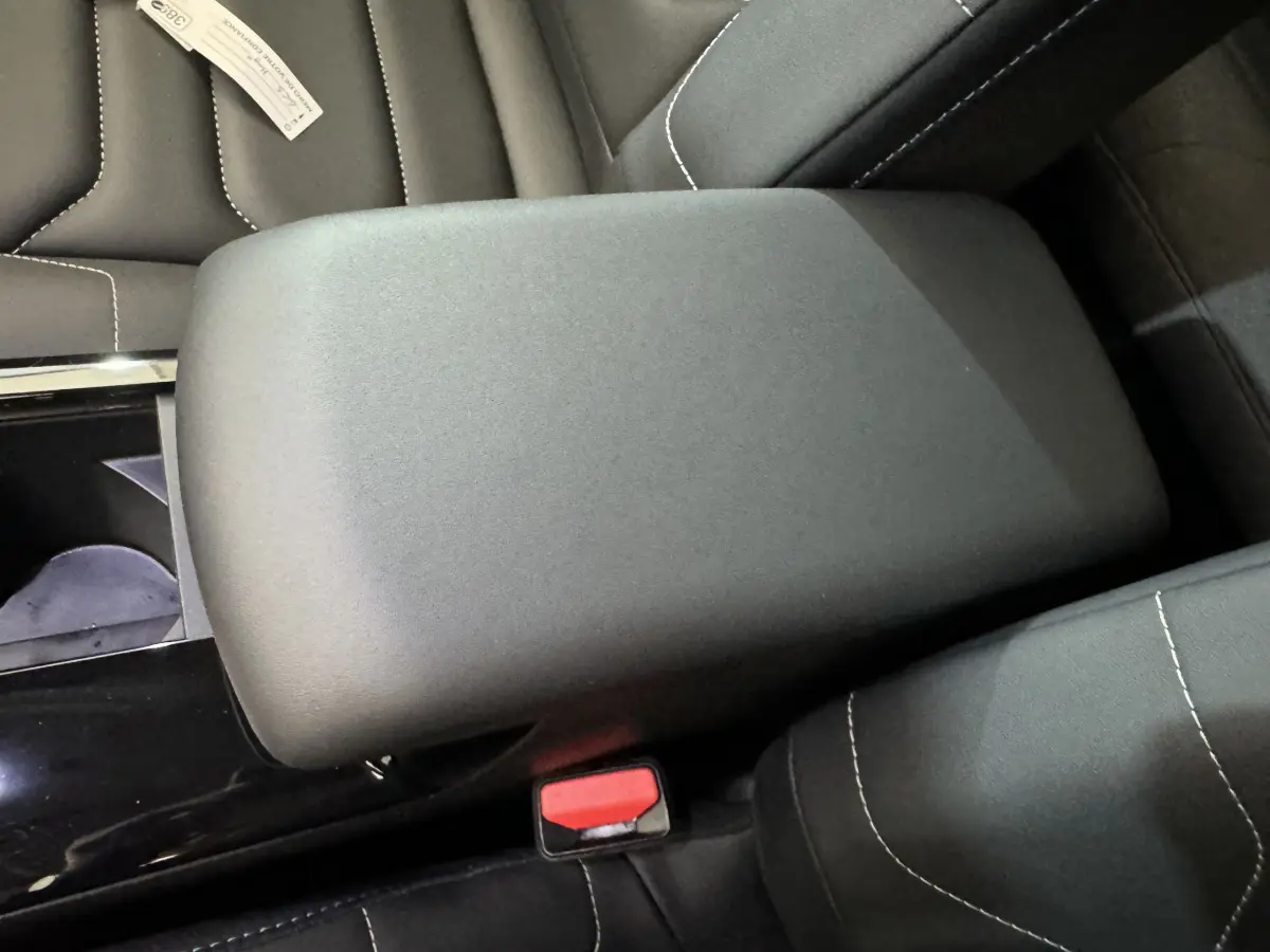 Gros plan sur l'accoudoir central noir et les sièges en tissu avec surpiqûres blanches d'une Citroën C4 PureTech 130 Shine 2023.