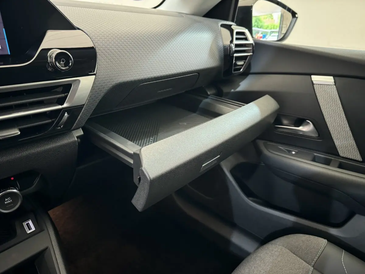 Intérieur de la Citroën C4 PureTech 130 noir, vue côté passager avec boîte à gants ouverte et tableau de bord texturé.