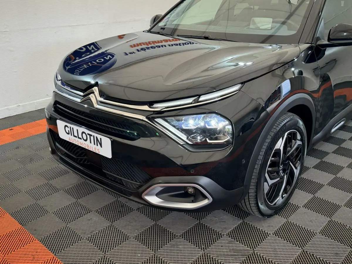 Vue 3/4 avant droit d'une Citroën C4 noire 2023 avec phares LED allumés et jantes alliage distinctives.