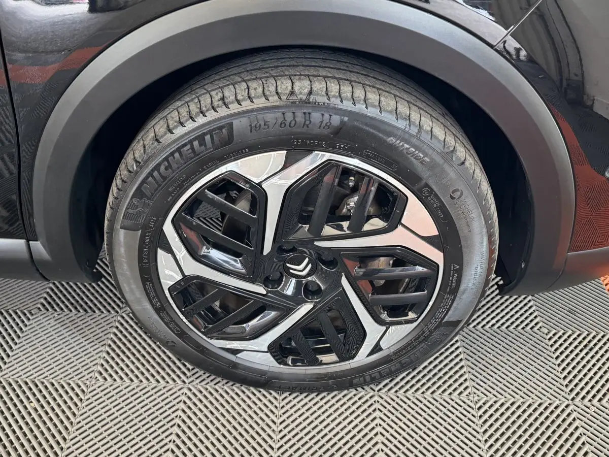 Gros plan sur la roue avant droite noire d'une Citroën C4 2023 avec jante en alliage au design moderne.