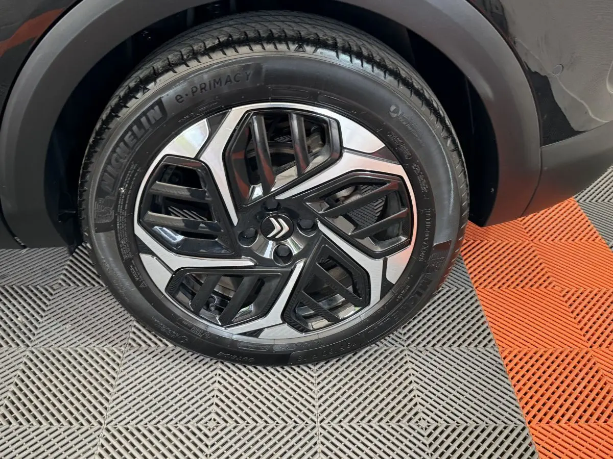 Gros plan sur la roue avant droite noire de la Citroën C4 PureTech 130 EAT8 Shine avec jante alu bicolore design.