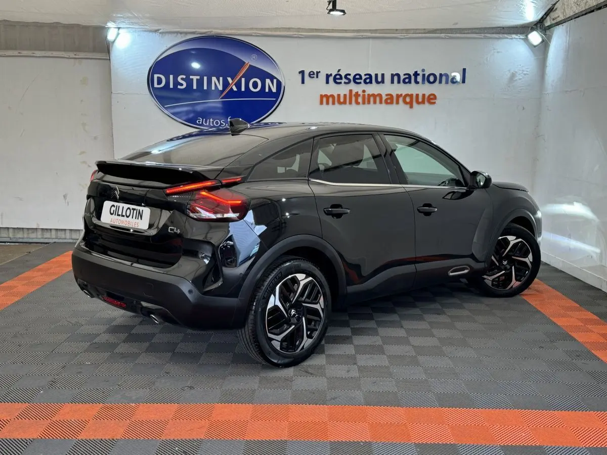 Citroën C4 noir vue 3/4 arrière droit en intérieur, avec feux arrière LED et jantes distinctives.