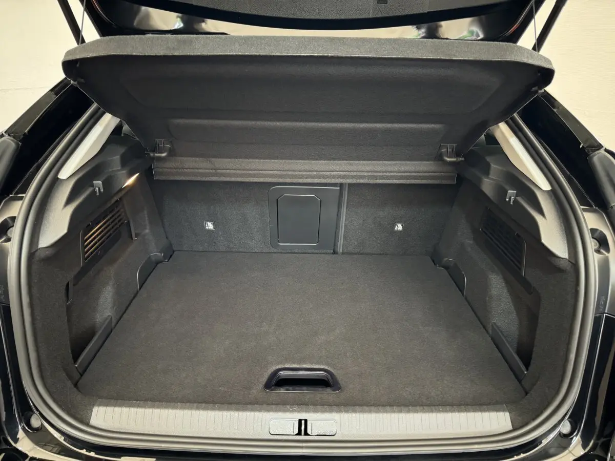 Coffre ouvert vu de l'arrière d'une Citroën C4 PureTech 130 noire, espace de chargement propre et spacieux.