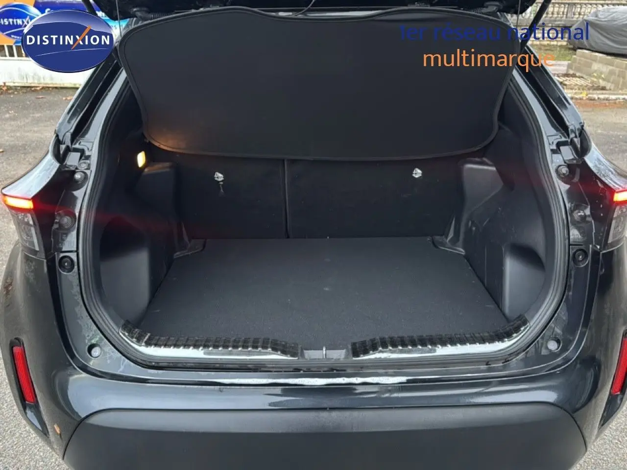 Coffre ouvert en vue arrière d'une Toyota Yaris Cross 116h Design noire 2023, montrant l'espace de chargement vide.