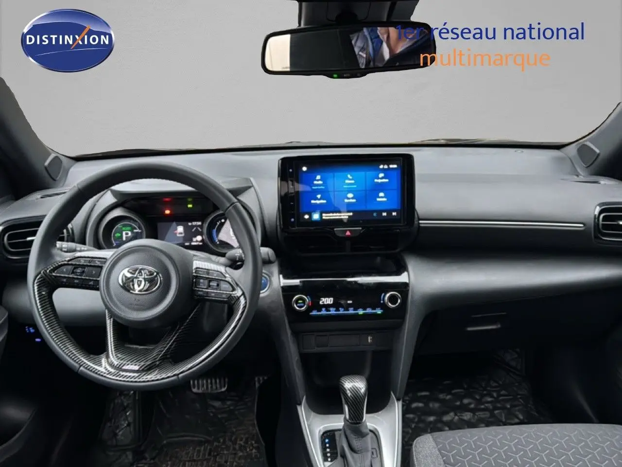 Vue intérieure avant du Toyota Yaris Cross noir 2023, tableau de bord moderne avec écran tactile central et volant multifonction.