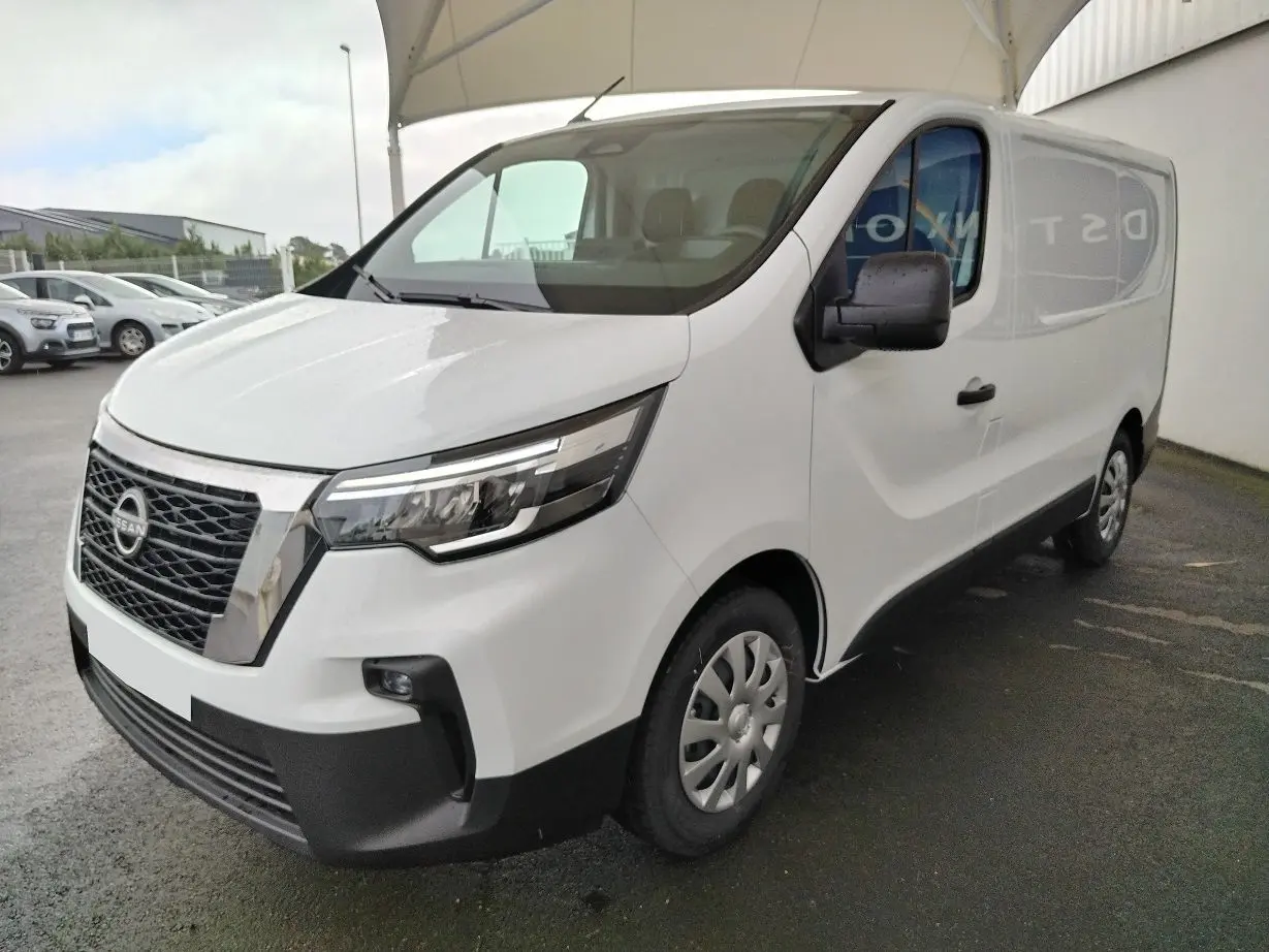 Nissan Primastar blanc en vue 3/4 avant droit, fourgon utilitaire avec calandre noire et jantes acier.