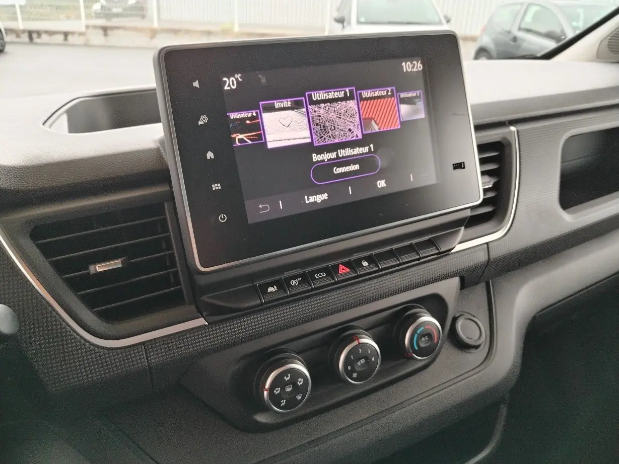 Vue rapprochée du tableau de bord du Nissan Primastar 2025 avec écran tactile et commandes de climatisation.