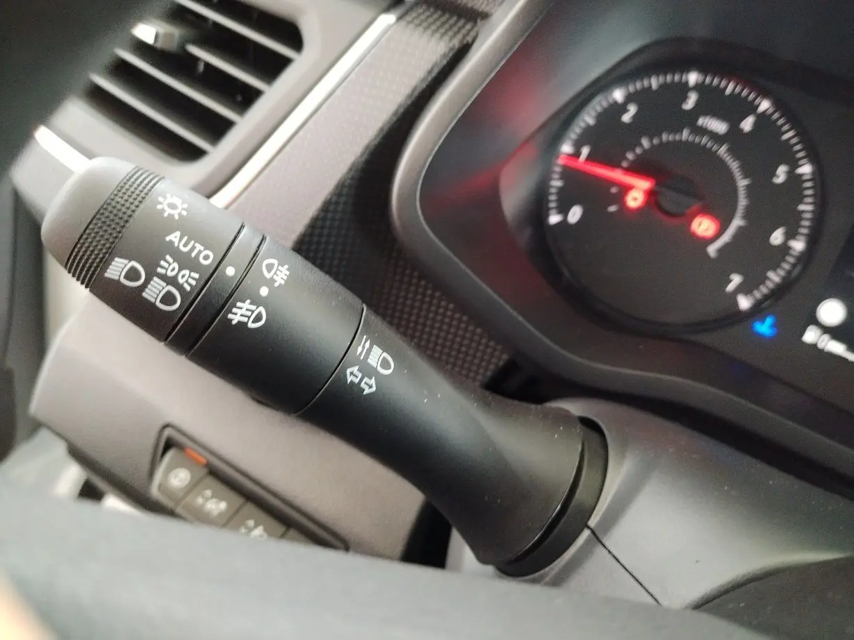 Gros plan sur la manette des phares et clignotants du tableau de bord du Nissan Primastar blanc 2025.