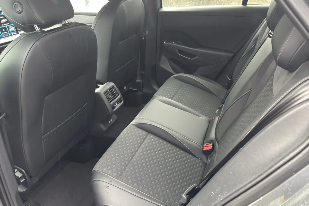 Vue intérieure arrière droite du Volkswagen T-Roc 2026, sièges tissu et cuir gris avec surpiqûres blanches.