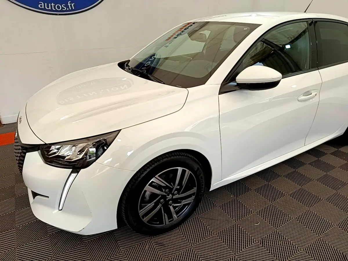 Peugeot 208 blanc vue 3/4 avant droit, avec phares LED et jantes alliage noires distinctives.