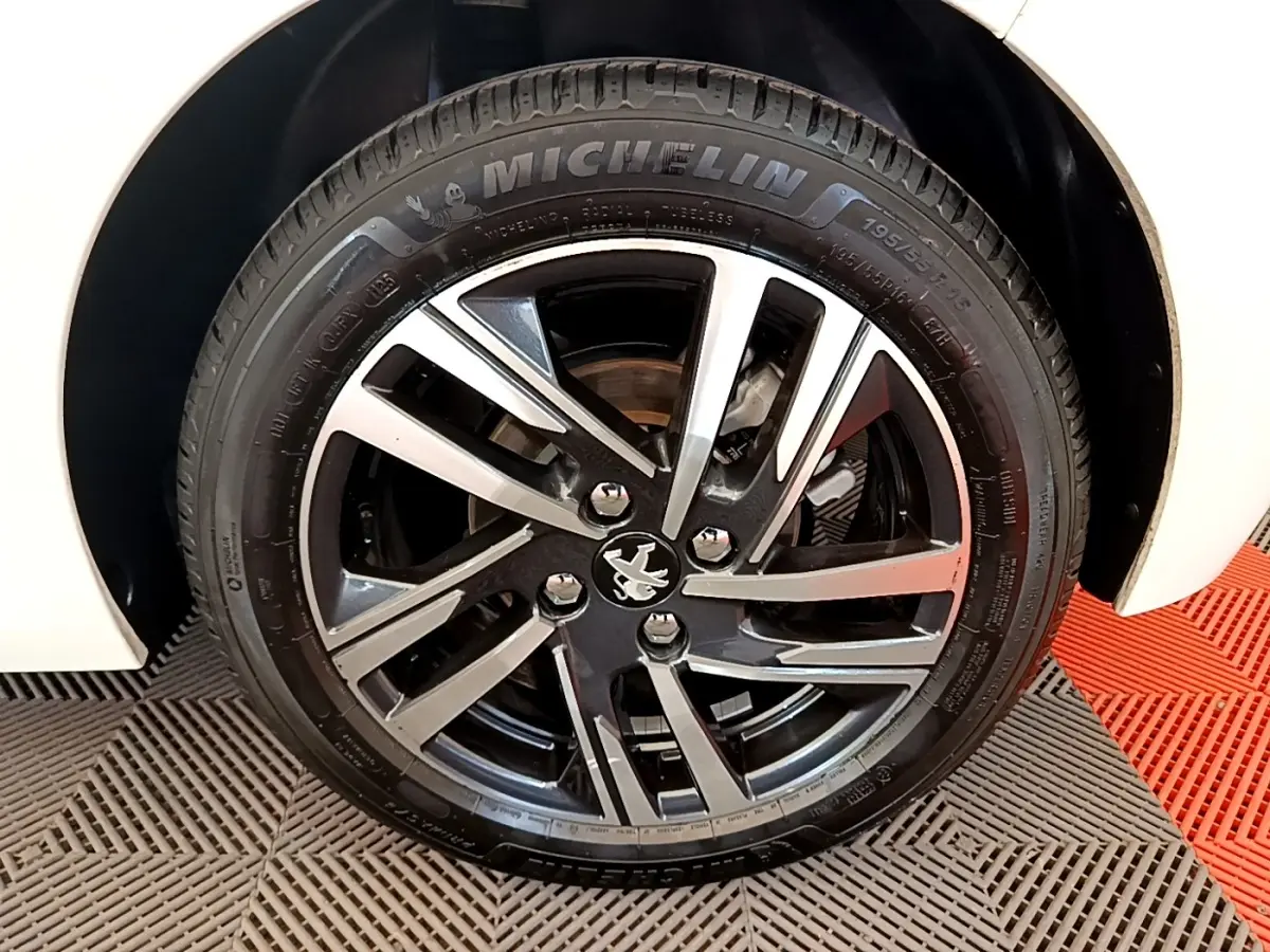 Gros plan sur la roue avant droite blanche d'une Peugeot 208 avec jante alliage bicolore et pneu Michelin.