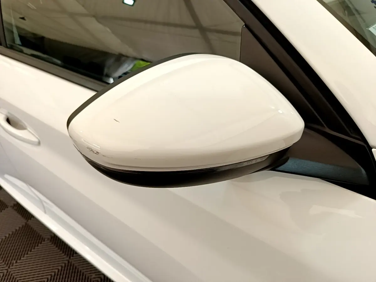 Rétroviseur droit blanc de la Peugeot 208 PureTech 100 S&S Allure Business vue en gros plan sur porte blanche.