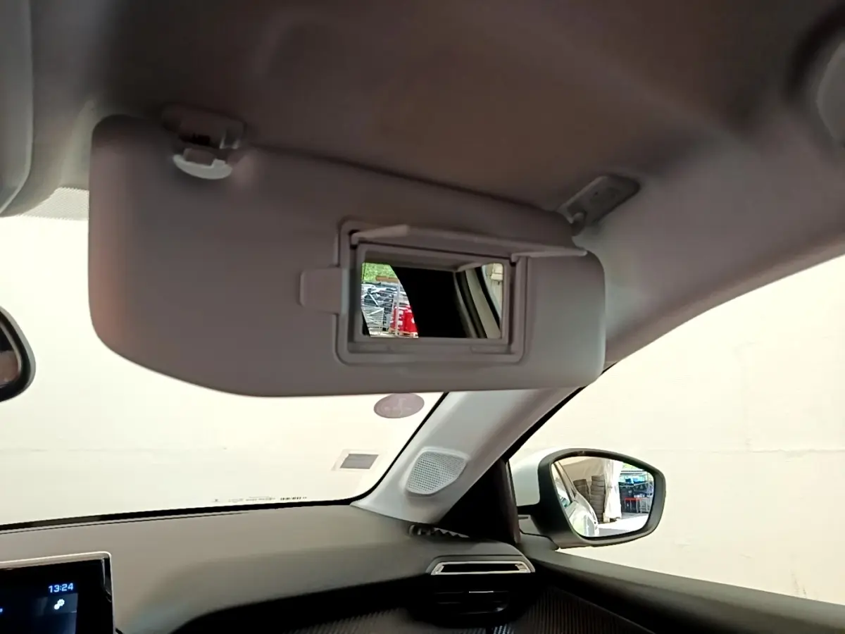 Intérieur du Peugeot 208 blanc, vue côté droit sur pare-soleil avec miroir et rétroviseur extérieur.