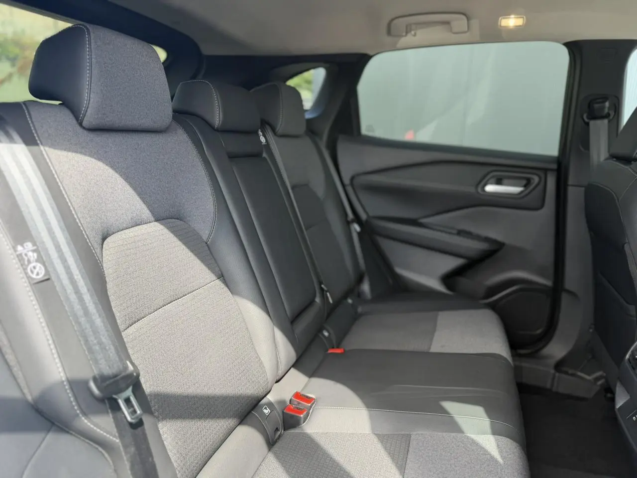 Vue latérale droite de l'habitacle arrière du Nissan Qashqai 2025, sièges mixte tissu et TEP noirs.
