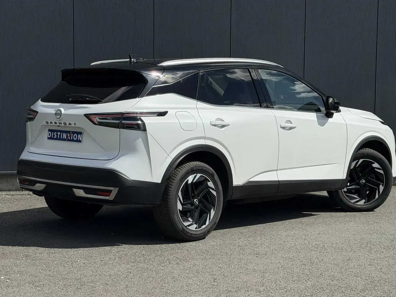 Vue 3/4 arrière droite du Nissan Qashqai blanc nacré avec toit noir et jantes alliage noires.