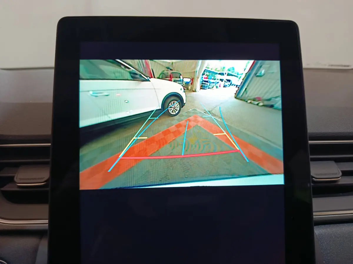 Vue écran caméra de recul montrant un Renault Captur blanc garé côté gauche dans un garage.