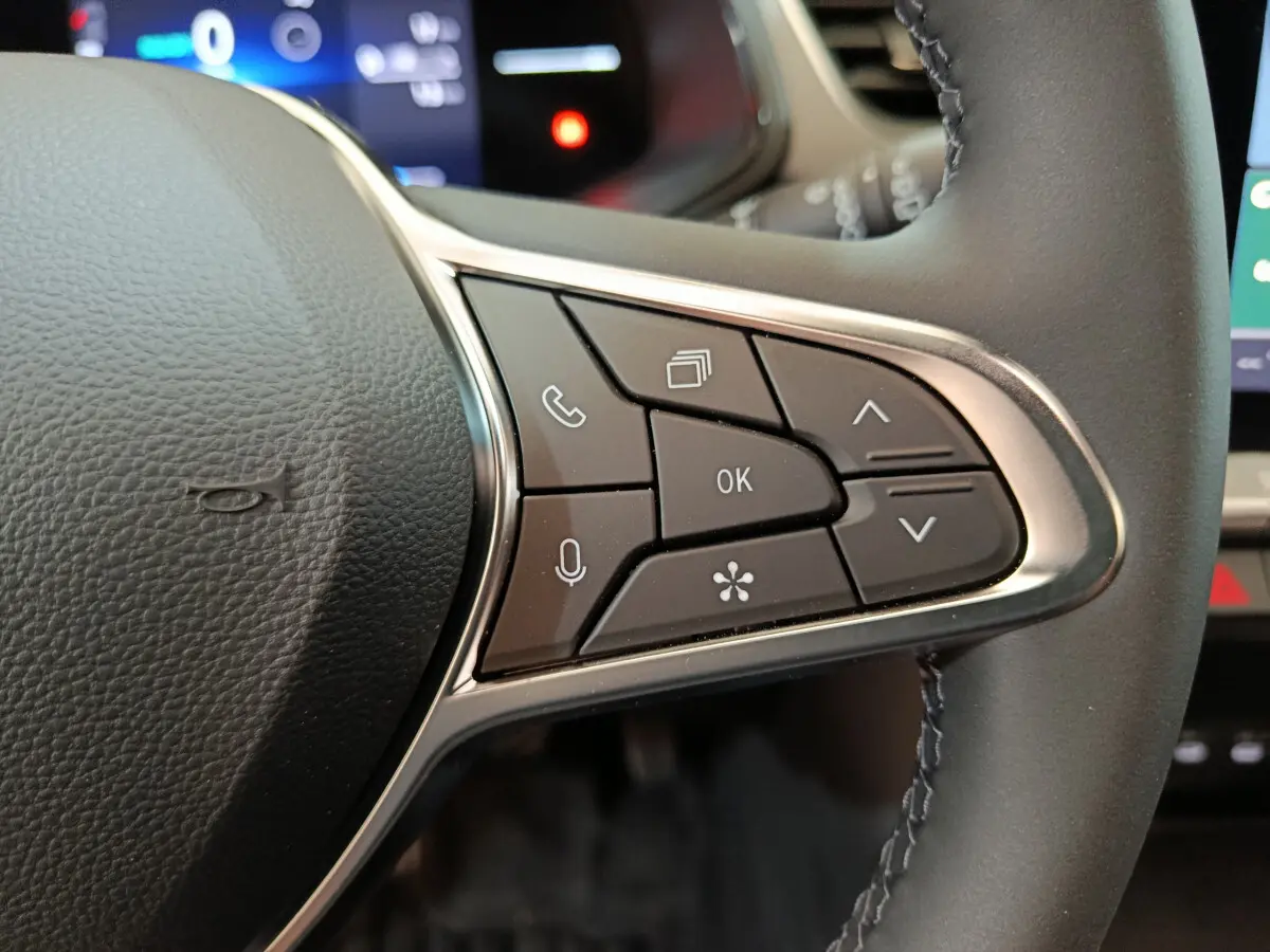 Gros plan sur les commandes multifonctions à droite du volant cuir du Renault Captur blanc techno E-Tech 2025.