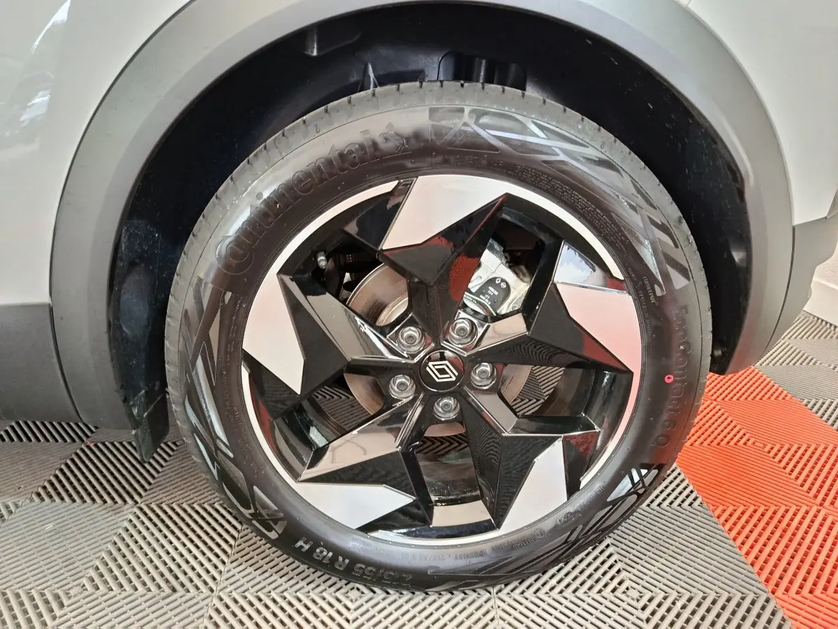 Gros plan sur la roue avant droite blanche du Renault Captur 2025 avec jante noire et argentée au design géométrique.