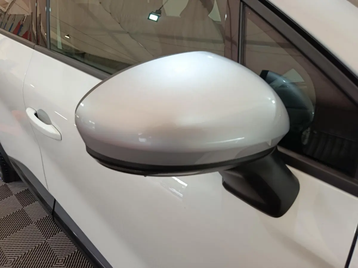 Rétroviseur côté gauche blanc du Renault Captur 2025 techno E-Tech hybride, avec poignée de porte visible en arrière-plan.