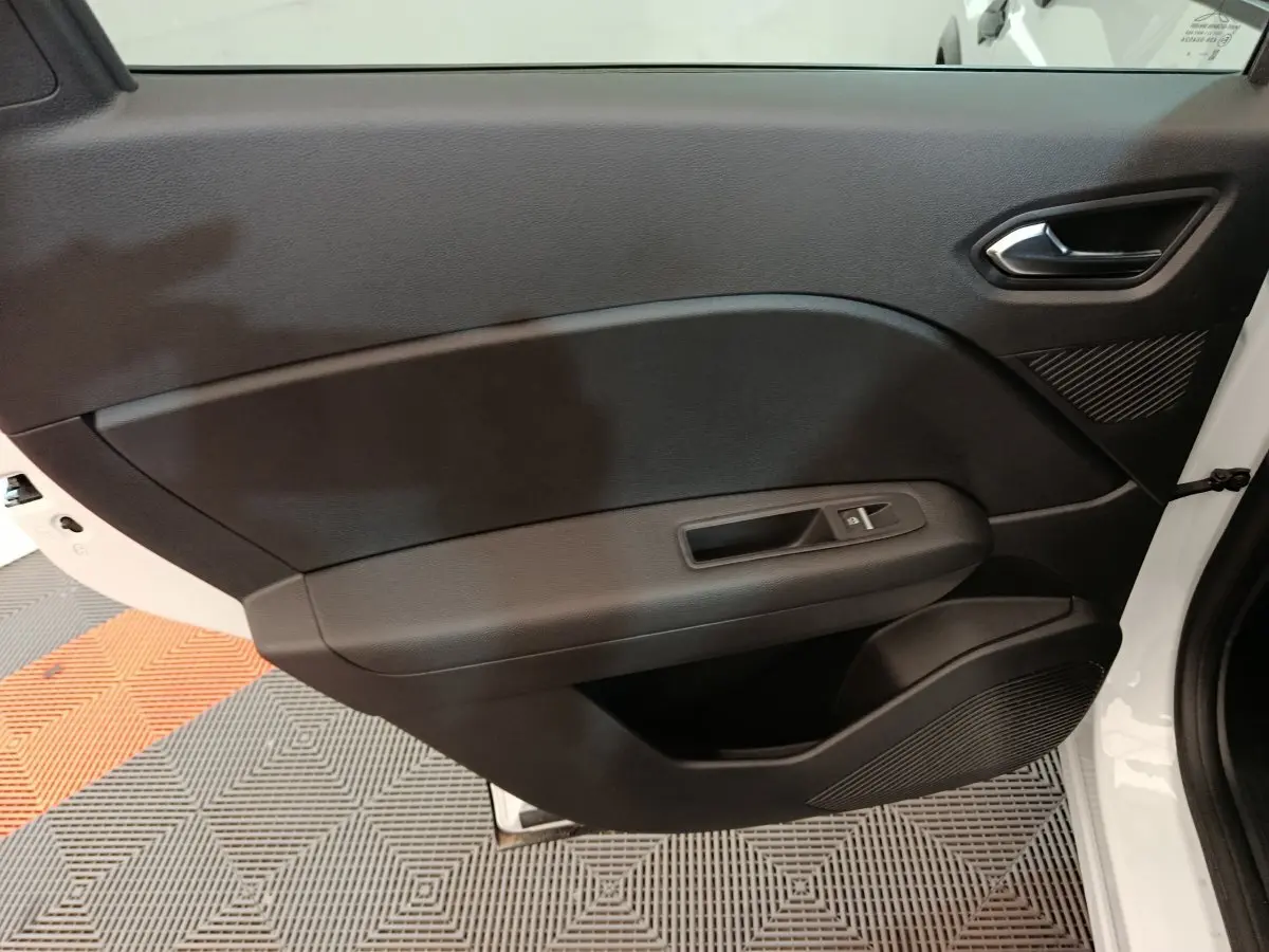 Vue intérieure côté gauche de la porte avant noire du Renault Captur blanc techno E-Tech 2025 avec poignée et commande vitre électrique.