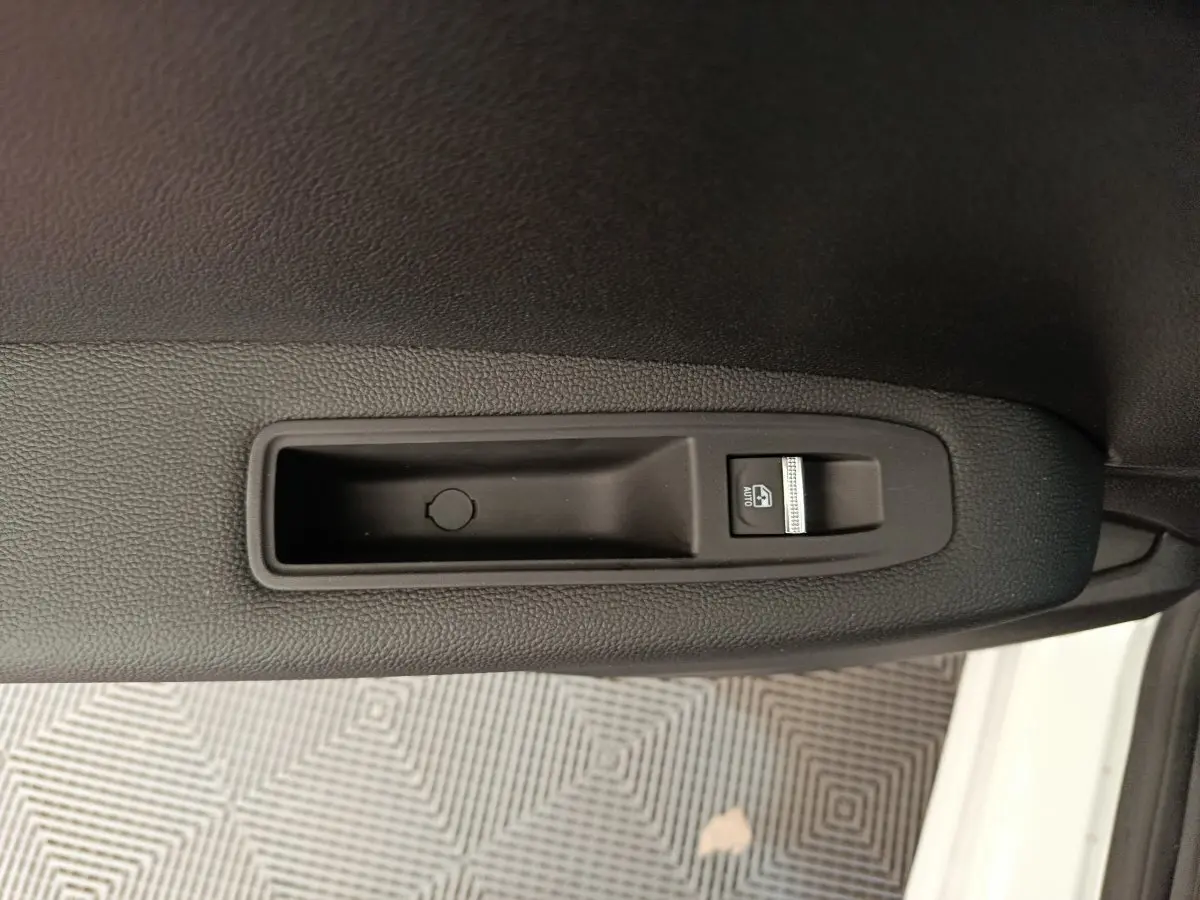 Gros plan sur le bouton de commande de la vitre électrique côté conducteur du Renault Captur blanc 2025.