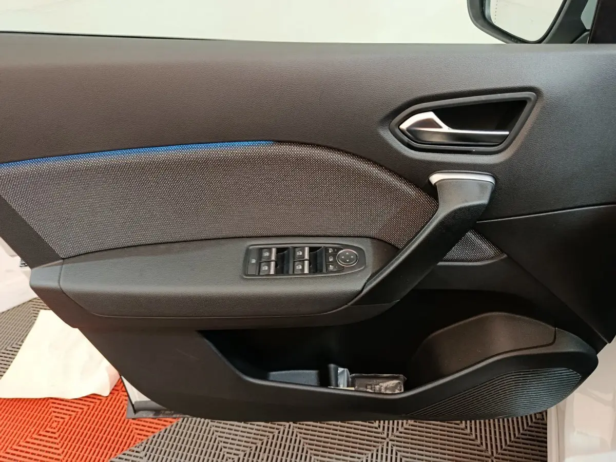 Vue intérieure côté gauche de la porte noire du Renault Captur blanc avec commandes de vitres et poignée argentée.