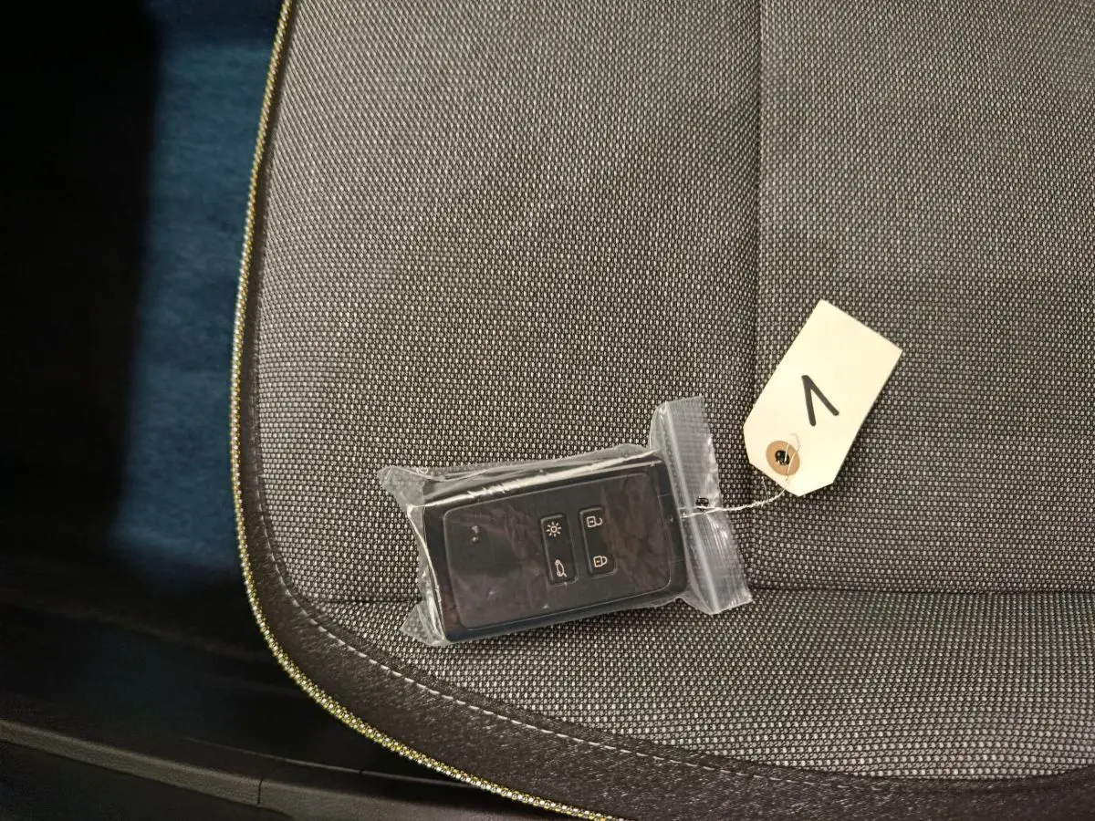 Gros plan sur la clé de démarrage Renault Captur 2025 posée sur un siège tissu gris foncé.