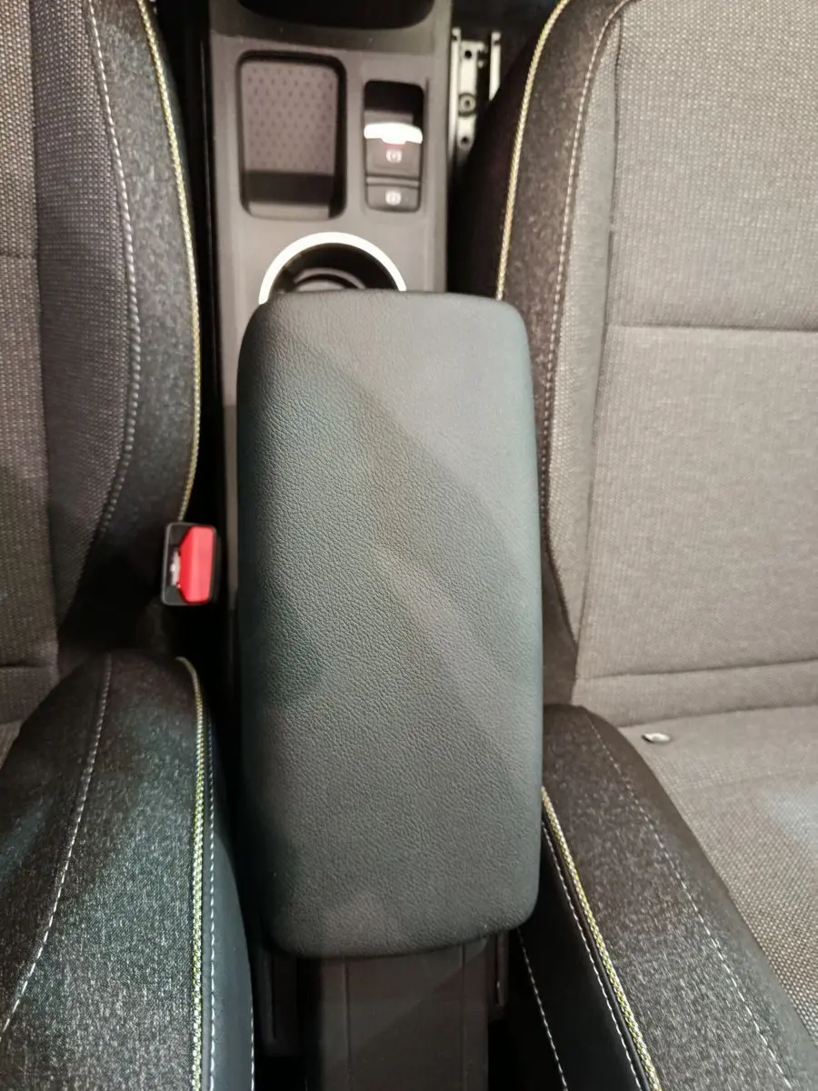 Vue plongeante sur l'accoudoir central en cuir synthétique noir entre les sièges avant du Renault Captur blanc 2025.