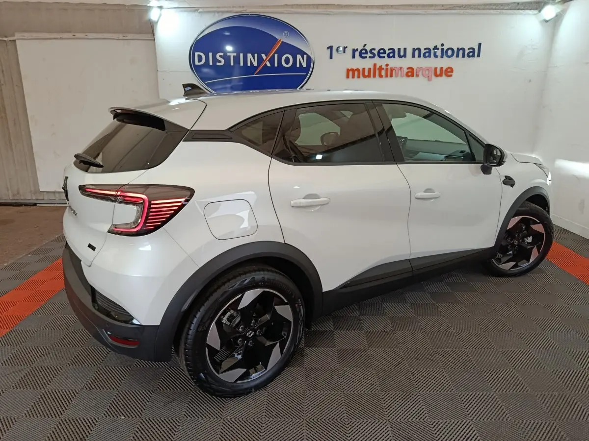 Renault Captur Techno E-Tech blanc vu de profil côté droit, avec jantes noires et feux arrière LED allumés.