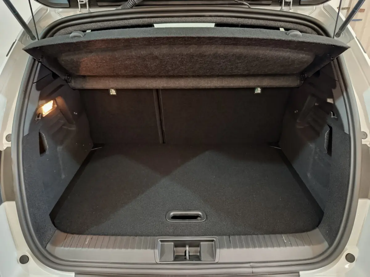 Coffre ouvert vu de l'arrière d'un Renault Captur blanc 2025, montrant un espace de rangement noir et propre.