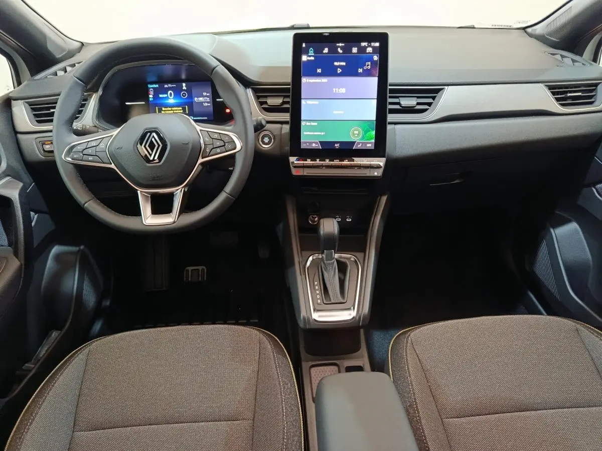 Intérieur du Renault Captur Techno E-Tech 2025, vue frontale du tableau de bord avec écran tactile vertical et volant multifonctions.