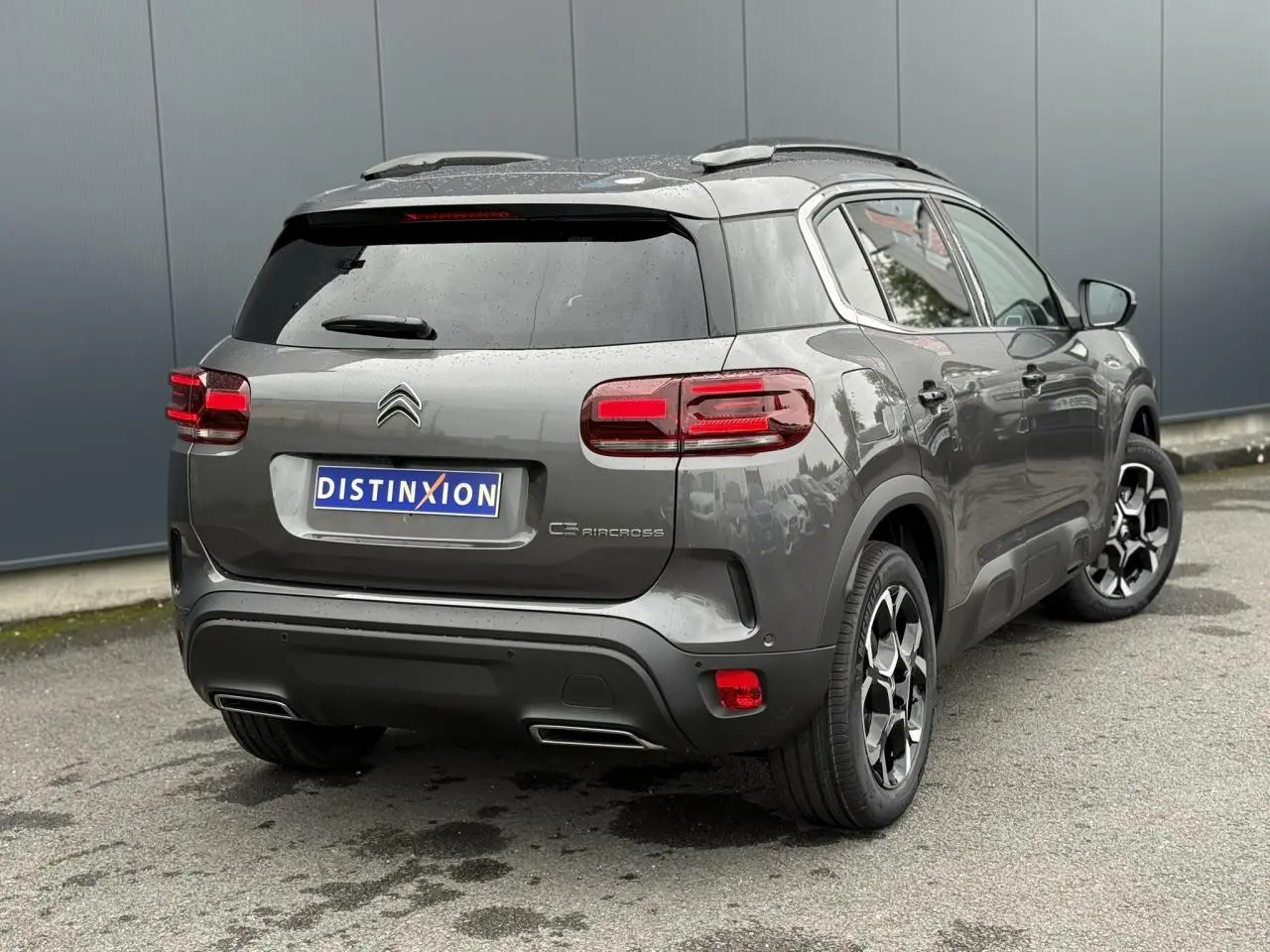 Vue 3/4 arrière droite d'un Citroën C5 Aircross gris Platinium avec jantes alliage bi-ton et toit noir Perla Nera.