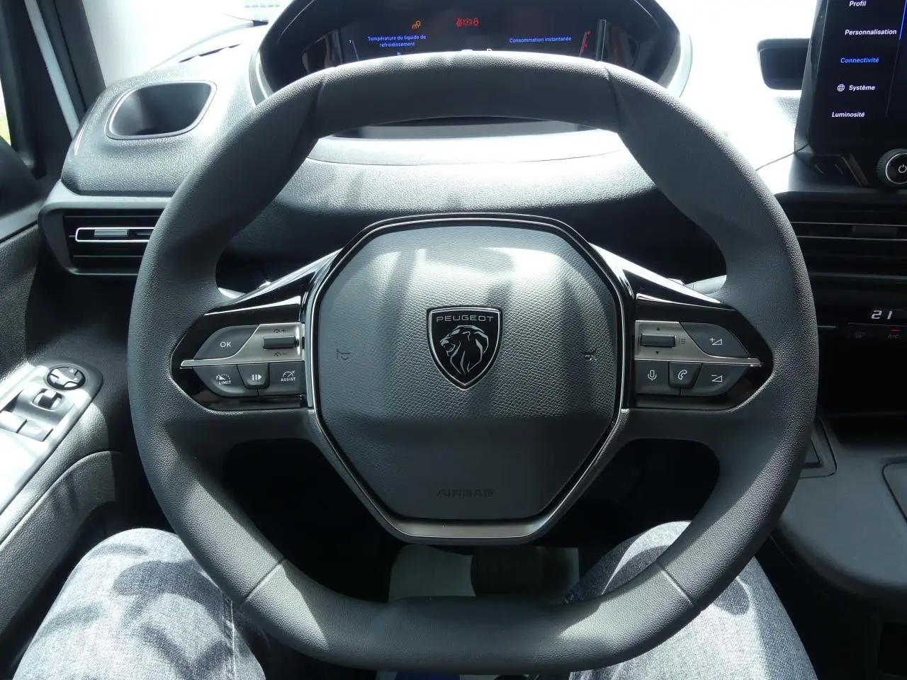 Volant multifonctions noir de Peugeot Partner 2025 vu de face avec tableau de bord numérique en arrière-plan.