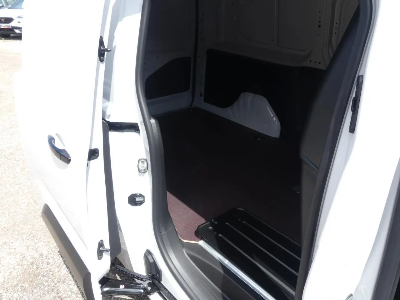 Vue rapprochée de l'ouverture de la porte latérale droite du Peugeot Partner XL blanc, montrant l'intérieur vide et le seuil de chargement.