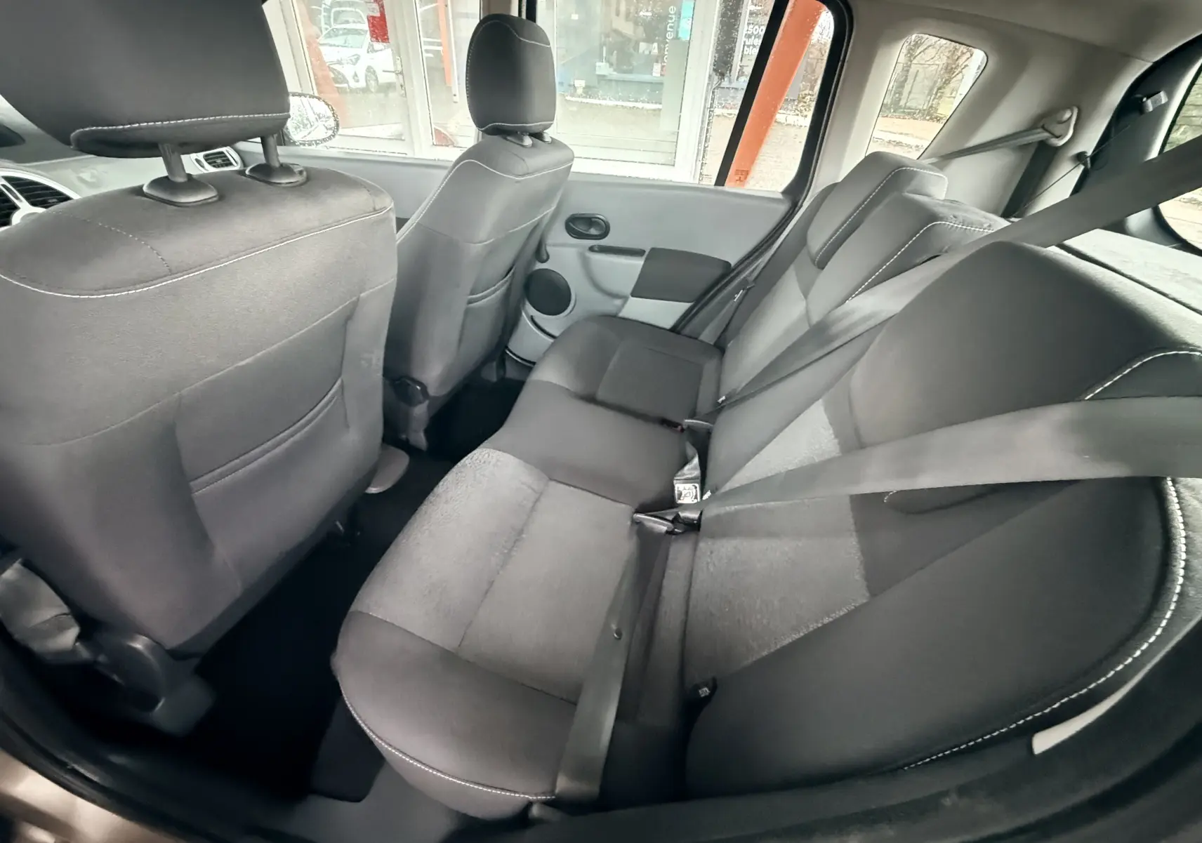 Vue intérieure arrière montrant les sièges en tissu gris noir et les ceintures de sécurité de la Renault Modus 2011.