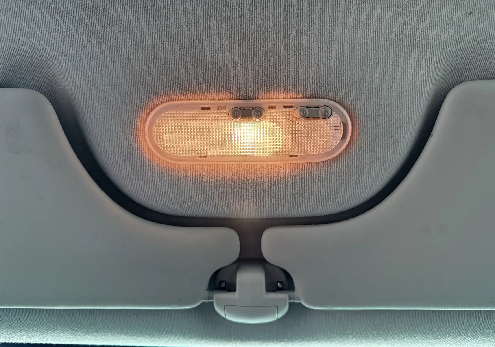 Plafonnier intérieur allumé avec deux pare-soleil gris clair dans une Renault Modus beige de 2011.