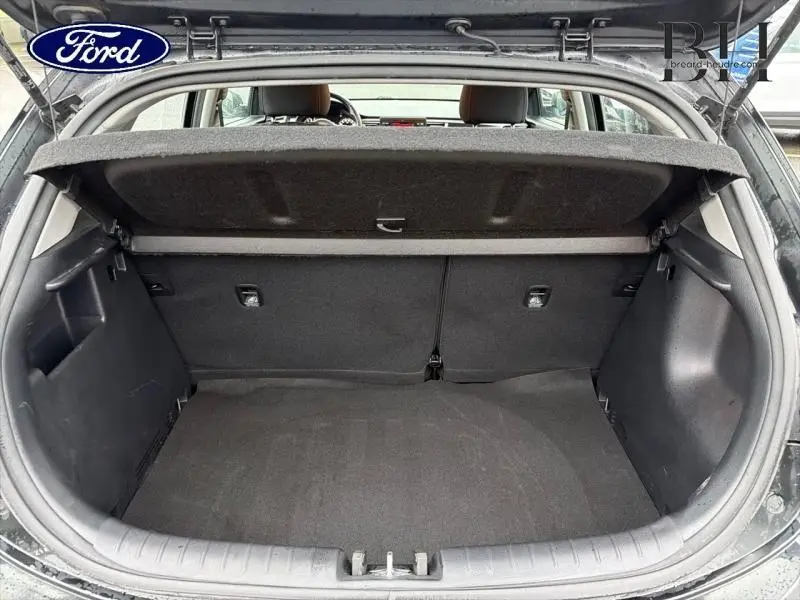 Coffre ouvert vu de l'arrière d'une KIA Rio noir Ébène, montrant l'espace de chargement et la tablette cache-bagages.