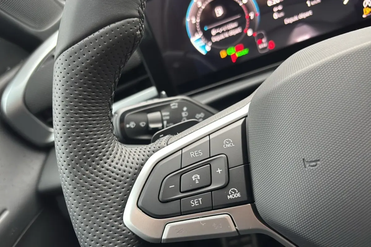 Gros plan sur le volant cuir perforé multifonctions du Volkswagen T-Roc 2026 avec commandes de régulateur adaptatif.